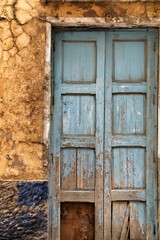 Old blue wooden door and damaged wall