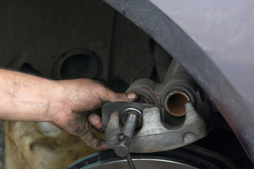 Replacement of worn disc brake system of the car. The mechanic carries out maintenance of brakes. Garage repair of the car.