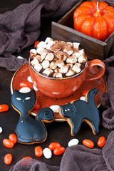 Ceramic mug with hot chocolate, marshmallows and gingerbread cookies for Halloween