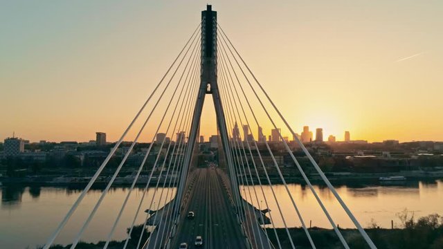 Aerial Geometry Pespective View of Suspension Bridge with Warsaw Skyline, capital of Poland (Warszawa, Polska). Urban Downtown Cityscape at Sunset. 4K Tilt Background Drone view Video with Copy Space