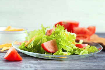 Leaf lettuce salad with tomatoes on a glass plate.