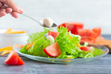 Leaf lettuce salad with tomatoes and mozzarella on a glass plate.