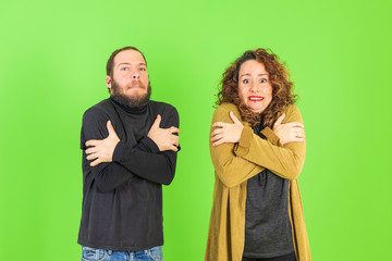 Young beautiful couple together over green background feeling cold and coughing as symptom for cold or bronchitis. Healthcare concept.