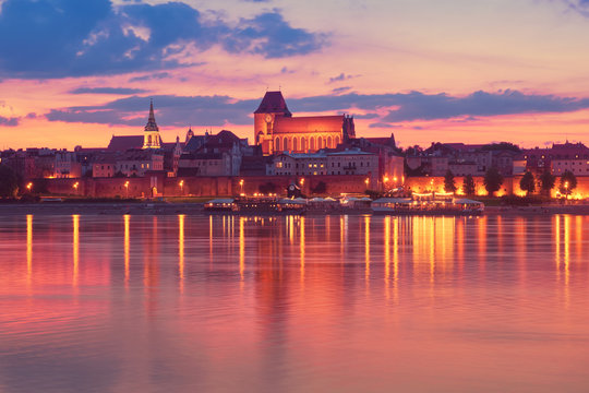 Torun old town in Poland, UNESCO world heritage site, with illumination, reflected in Vistula river on sunset sunset.