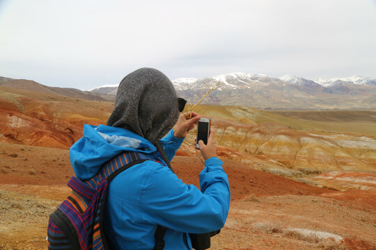Woman traveller taking photo of red mountains in Altai in Russia. Valley of Mars landscapes in the Altai Mountains, Kyzyl Chin, Siberia, Russia