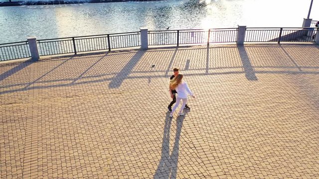 Modern dancers are dancing in the street. Urban lifestyle. Hip-hop generation. Boy's and girl's emotional moves on the video. Paving stones and young dacing couple at fontain background. Aerial view. 