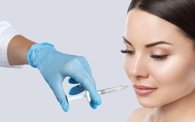 The doctor cosmetologist makes Lip augmentation procedure of a beautiful woman in a beauty...