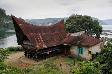 Parapat, Sumatra - January 30, 2018: unusual traditional houses with boat roofs of the Batak people on the island of Sumatra, Indonesia. The traditional architecture of Batak Indonesia.