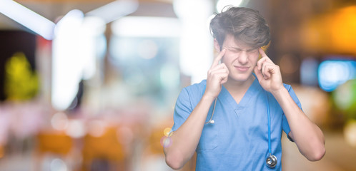 Young doctor wearing medical uniform over isolated background with hand on head for pain in head because stress. Suffering migraine.