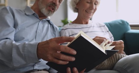Grandparents couple spend leisure time at home reading book knitting - Powered by Adobe