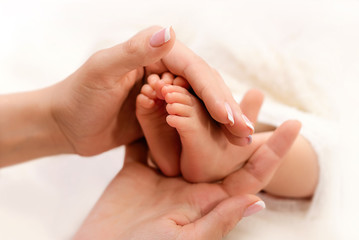 Newborn. Mom's hands hold the legs of a baby