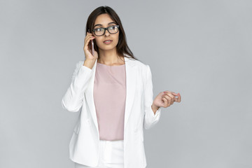 Serious young adult Indian business lady professional looking away talking on modern phone having...