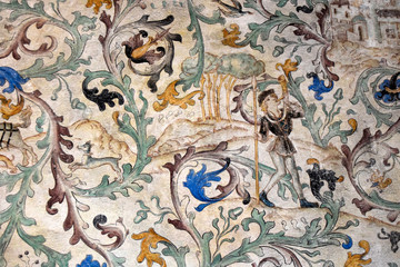 Fragment of the ancient castle wall. There is a fresco on the wall. The painting shows a man, a...