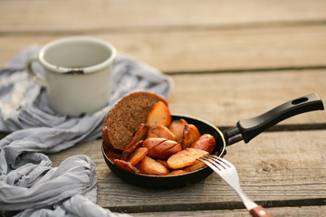  Country-style potatoes with sausages fried in oil.Chips with fried sausages in a pan. Fried potatoes with sausages, onions, garlic, caraway seeds, pepper and seasonings. Fried eggs on a fire 