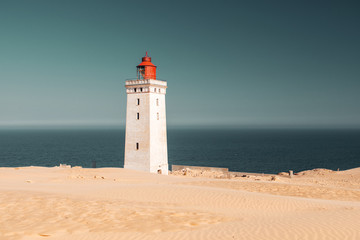 Fototapeta na wymiar White beach sand dunes at the north danish coastline in summer sun light and blue sky. Rubjerg Knude Lighthouse, Lønstrup in North Jutland in Denmark, Skagerrak, North Sea