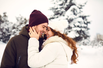 Young couple on the snow in winter in the park