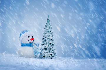 Merry christmas and happy new year greeting card .Ñheerful snowman with Christmas tree standing in winter christmas landscape