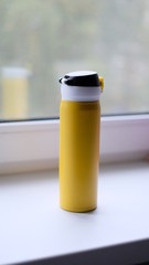 yellow thermos with black standing on the window