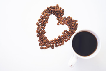Heart shape made from coffee beans with cup of coffee on white background. I love coffee