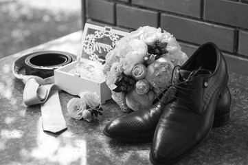 Fototapeta na wymiar Wedding details. Bridal bouquet, shoes, invitation cards, rings and veil on a pink armchair. Black and white photo