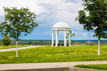 White rotunda on a background of blue sky and flowering chestnuts