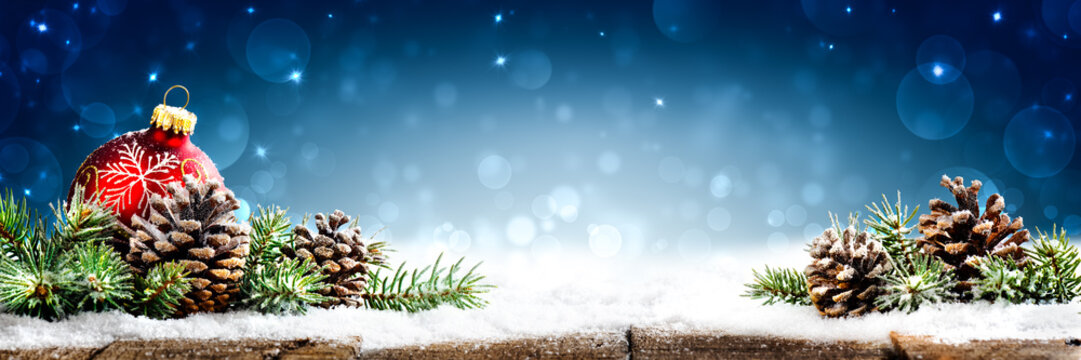 Christmas - Banner Of Red Ornament, Pine-cones And Branches On Snowy Wooden Table With Blue Bokeh Background
