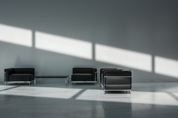 Empty corporate lobby with leather chairs and shadow across wall