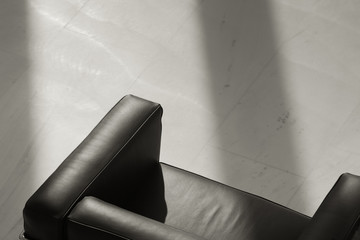 Close up of black leather chair in office lobby with shadow 