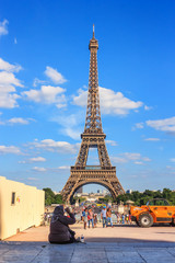 Summer city landscape - view of a woman tourist hiding from the heat in the shade against the background of the Eiffel Tower, on a hot summer day in Paris