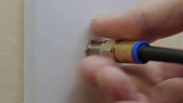 Male electrician disconnecting coax cable cord from wall outlet. Coaxial wire connection for TV and high speed broadband internet. Canceling television service.