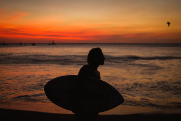 young man with surf table at sunset