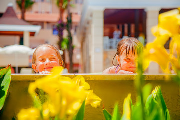 Holidays in hot countries concept. Side view of two child girl friends playing and having fun in swimming  pool.