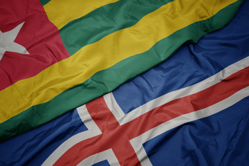 waving colorful flag of iceland and national flag of togo.