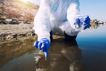 Conserve water and environment. Shot of an unrecognizable ecologist taking samples of water with...