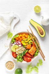 Buddha bowl with grilled salmon fish, fresh cucumber, tomato, onion, sweet pepper, avocado, lettuce salad and rice, healthy balanced eating