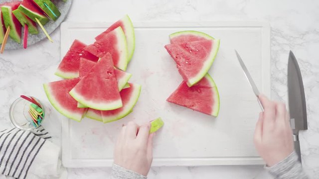 Flat lay. Slicing red watermelon into small pieces on a white cutting board.