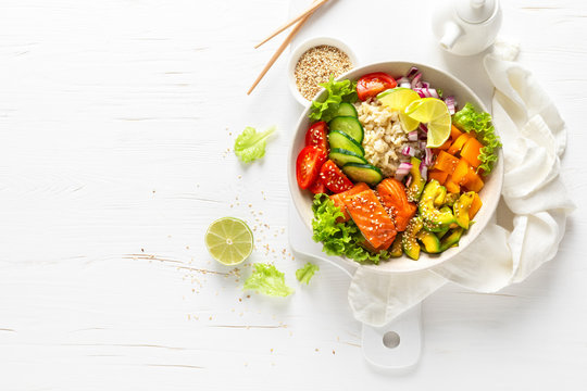 Buddha bowl with grilled salmon fish, fresh cucumber, tomato, onion, sweet pepper, avocado, lettuce salad and rice, healthy balanced eating