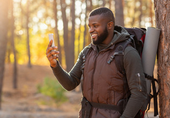 Cheerful guy taking photos of autumn forest