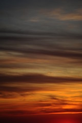 Fototapeta na wymiar Cielo al tramonto, la luce sulle nuvole crea una texture dai colori caldi 