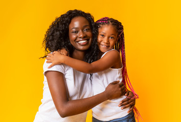 African american mother and daughter cuddling and posing to camera