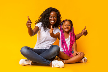Mother and Daughter Gesturing Thumbs Up Over Yellow Background.