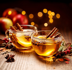 Mulled cider with apple slices, cinnamon, cloves, anise stars and citrus fruits in glass cups on a...