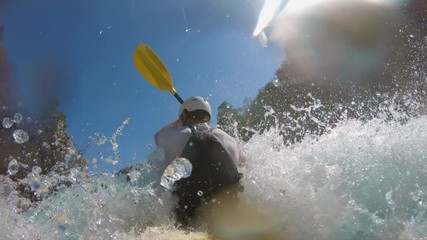 A man kayaking through rapids, filmed in slow motion