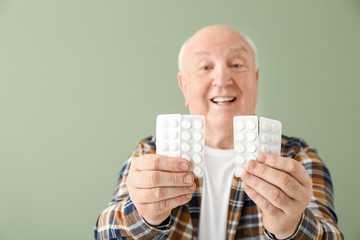 Elderly man with pills on color background - obrazy, fototapety, plakaty
