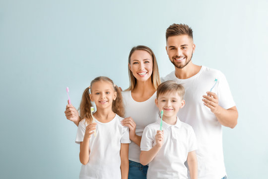 Portrait of family with toothbrushes on light background