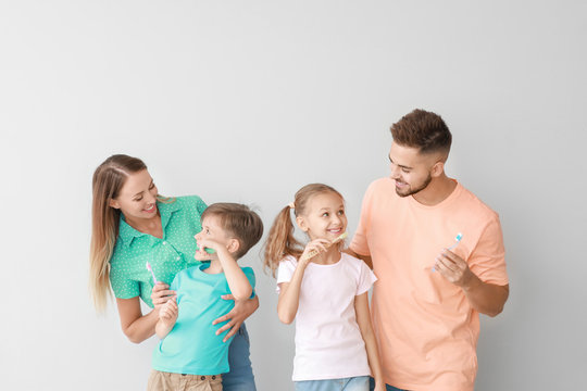 Portrait Of Family Brushing Teeth On Light Background