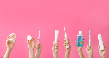 Female hands with toothbrushes, paste, mouth rinse, dental floss and model of jaw on color...