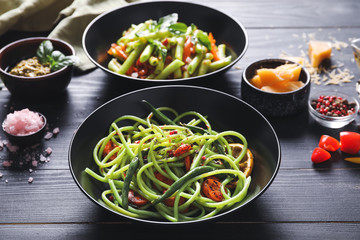 Plate with tasty green pasta on dark table