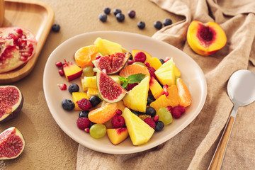 Plate with tasty fruit salad on table