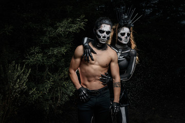 Naklejka premium Pareja de jóvenes pesados maquillados de calaveras en halloween